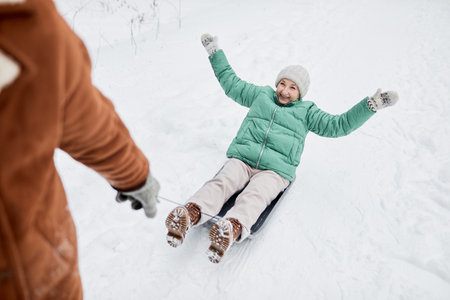 Husband pulling sled with happy excited wife sitt on itの写真素材