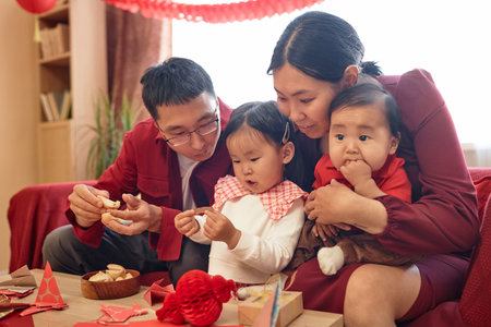 Portrait of happy Asian family with two children celebrating Chinese New Year together at home and opening fortune cookiesの写真素材