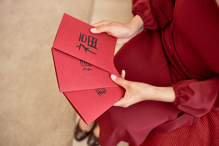 Close up of young woman holding red card with Chinese New Year blessings in traditional calligraphy...