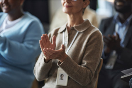 Hands of mature businesswoman in beige woolen pullover applauding to speaker at conference or...
