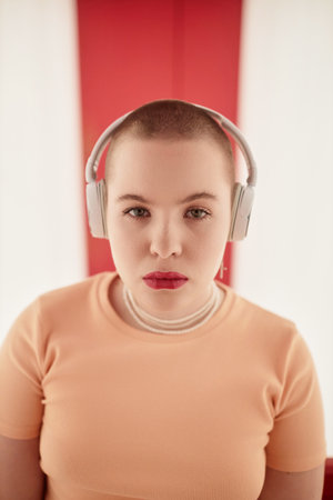 Graphic portrait of gen Z young woman wearing headphones and looking at camera with confidence in futuristic spaceの写真素材