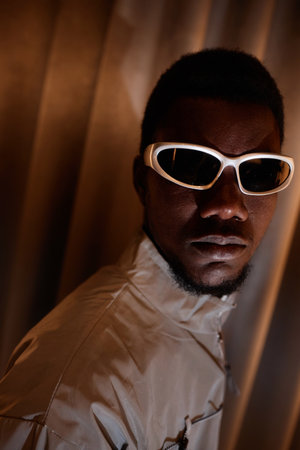 Close up fashion portrait of young Black man wearing 90s style sunglasses and looking at camera...