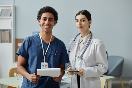 Waist up portrait of two young medical interns looking at camera standing in clinic office, copy...