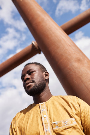 At angle shot of African American man looking away against sky with geometric shape