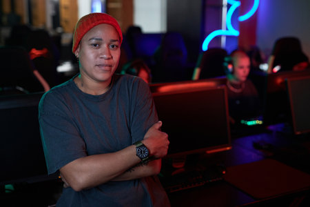 Waist up portrait of confident African American woman looking at camera standing in gaming club, copy spaceの写真素材