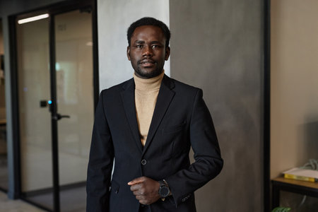 Waist up portrait of young stylish Black man at office building looking at cameraの写真素材