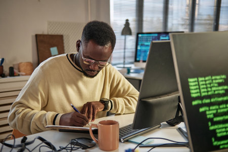 Software developer writing down plans for the day and ideas in notebook