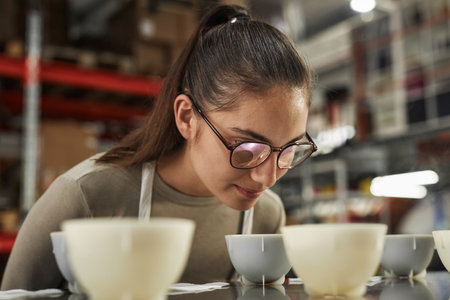 Close up of smiling young woman inspecting coffee quality during cupping process in artisanal coffee factory, copy spaceの写真素材