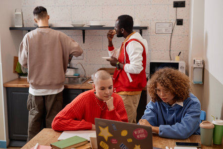 Multiethnic group of young students working on project together in kitchen interior at college dormの写真素材