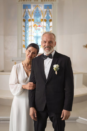 Vertical portrait of newlywed senior couple standing in church together and smiling at cameraの写真素材