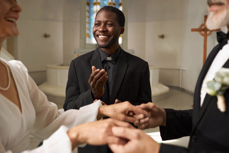 Waist up portrait of smiling Black man as priest officiating wedding in church, copy spaceの写真素材
