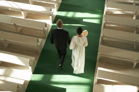 Top view at senior couple walking down aisle in church during wedding ceremony in sunlight, copy spaceの写真素材