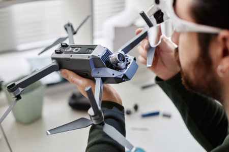 Close up of unrecognizable man holding drone with action camera in tech repair workshop, copy spaceの写真素材