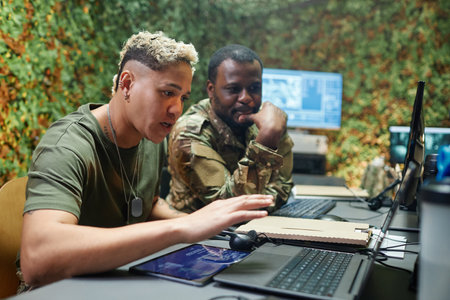 Young confident female officer of surveillance center explaining something to male colleague while...
