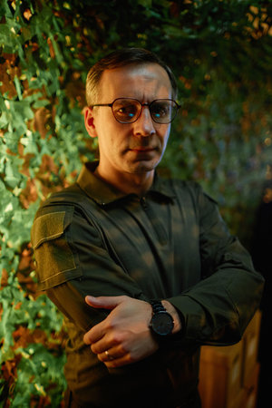 Confident mature male security officer in eyeglasses and uniform crossing his arms by chest and...