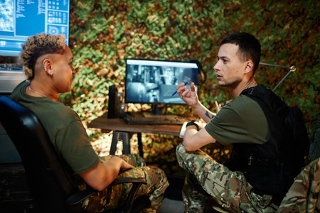 Young confident man in bulletproof vest explaining something to multiethnic female colleague during...
