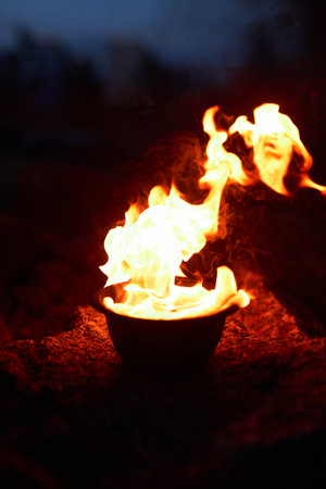 Vertical closeup of red flaming fire in bowl set for spiritual ritual outdoorsの写真素材
