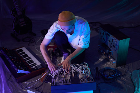 High angle shot of male musician sitting on floor of studio while experimenting with recorded audio samples using sound mixerの写真素材
