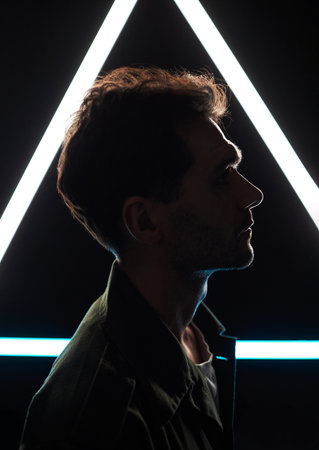 Side view of unrecognizable male silhouette on black background with white fluorescent lamp lightingの写真素材