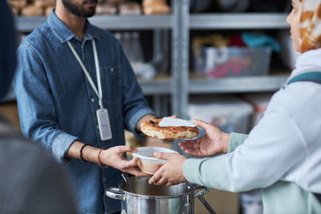 Close up of unrecognizable Middle Eastern man helping refugees at soup kitchen and giving out hot...