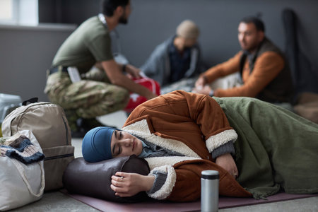Side view portrait of Middle Eastern woman wearing hijab sleeping on floor at refugee shelter with...