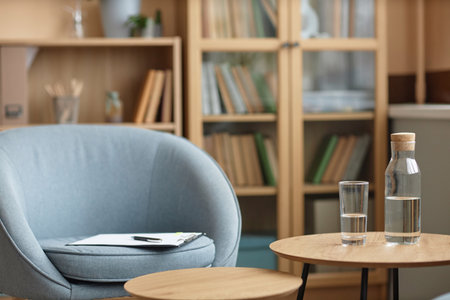 Close up of psychotherapists workplace with glass of clear water on table in therapy session, copy spaceの写真素材