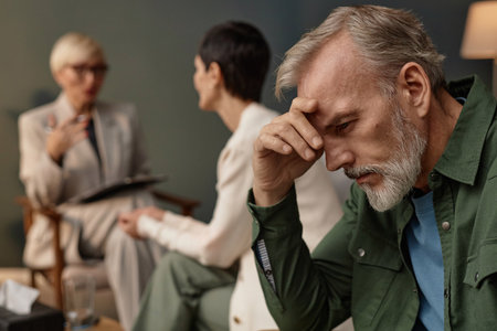 Side view portrait of distressed adult man holding head in hands during couples therapy session or counselling, copy spaceの写真素材