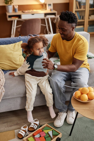 Vertical high angle shot of friendly Black father supporting his daughter during inhalation...