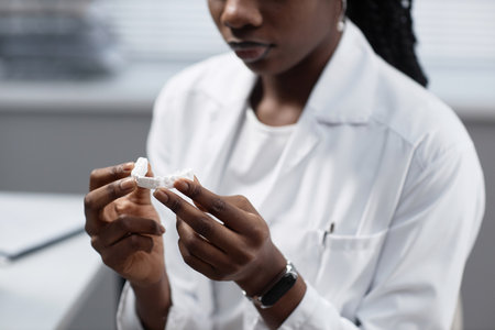 Cropped shot of African American female laboratory engineer holding printed 3D dental modelの写真素材