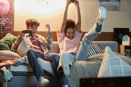 Portrait of two excited teen friends playing videogames together and celebrating victory
