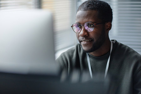 Closeup portrait of professional Black young man wearing glasses with computer screen reflection in office copy spaceの写真素材