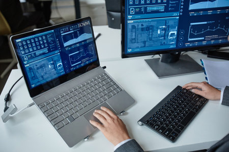 High angle closeup of professional IT security specialist using multiple computers with blue data on...