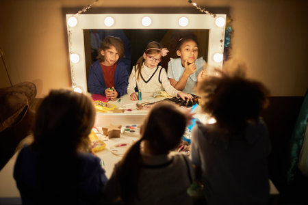 high angle portrait of three little children looking into mirror preparing for theater performers backstage with focus on reflectionの写真素材