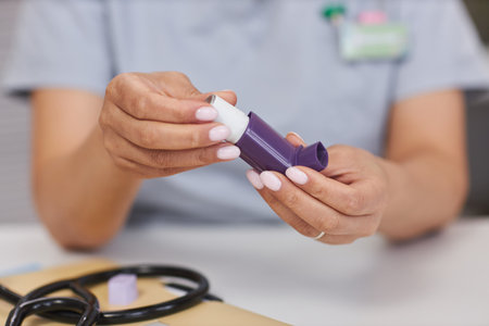 Close up of unrecognizable female doctor holding inhaler and demonstrating it to patent in clinic copy spaceの写真素材