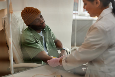 Portrait of African American man receiving chemotherapy treatment in procedure room at clinic behind...