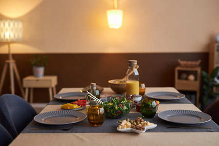 Background image of elegant dining room table with plates and dishes in cozy low light copy spaceの写真素材