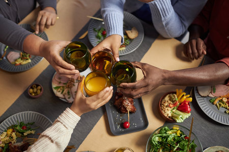 Top view closeup of big African American family clinking glasses in celebration over dinner tableの写真素材