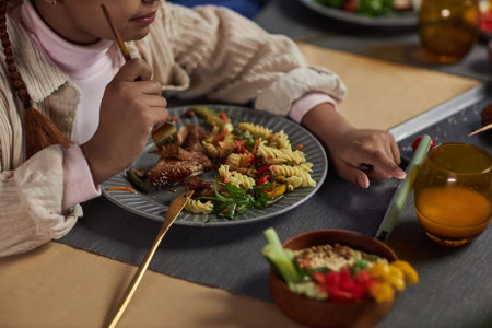 Closeup of young girl using smartphone while eating at dinner table and tapping screen copy spaceの写真素材