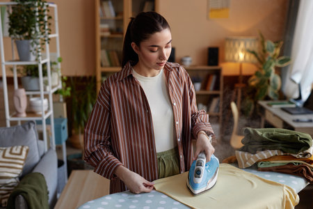 High angle portrait of young woman ironing clothes on laundry day and taking care of house chores copy spaceの写真素材