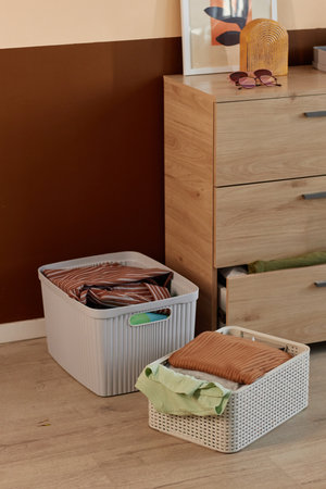 Background image of clean clothes in stacks and storage boxes in home interior