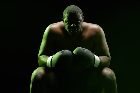 Dramatic backlit portrait of muscular African American boxer looking at camera with green outline
