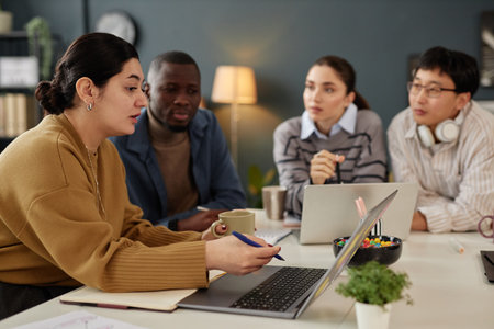 Side view portrait of Middle Eastern woman pointing at laptop screen while presenting ideas during...