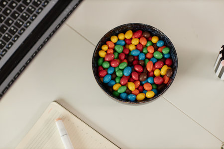 Minimal top view background image of white table or desk in office with focus on bowl of colorful...
