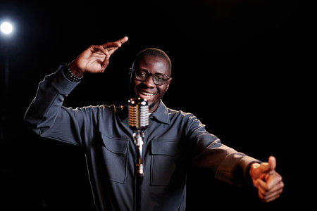 Minimal waist up portrait of emotional African American man speaking to microphone and performing on...