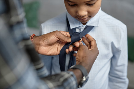 Close up of loving African American father tying tie for son first day of schoolの写真素材