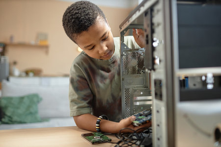 Portrait of young African American boy building PC computer and assembling parts, copy spaceの写真素材