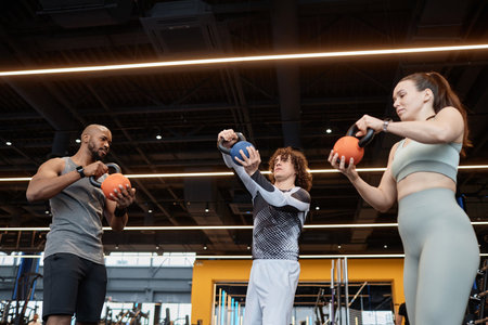 Low angle portrait of muscular Black man as fitness coach assisting clients and giving instructions...