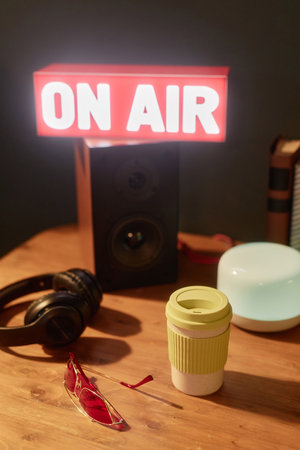 Vertical background image of light up On air sign in studio with speakers and podcast equipment