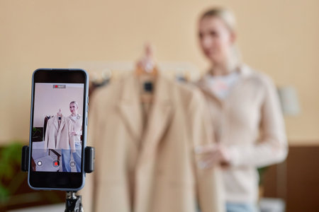 Background image of fashion stylist recording videos online for social media with focus on smartphone screen copy spaceの写真素材