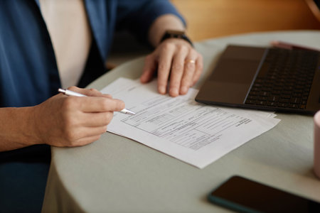 Close up of unrecognizable senior woman signing financial papers and doing taxes at home copy spaceの写真素材